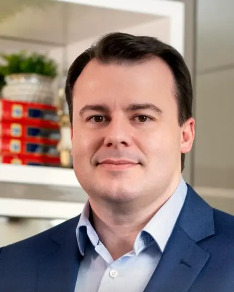 Dr. Roger Scalco, otorrinolaringologista, sorrindo no consultório do Centro
